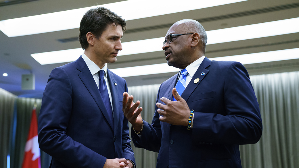 Prime Minister Justin Trudeau speaks with Prime Minister of The Bahamas Hubert Minnis in a conference room.