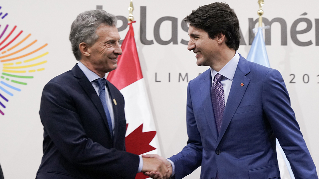Le premier ministre Justin Trudeau serre la main du président de l’Argentine Mauricio Macri dans une salle de conférence, devant des drapeaux du Canada et de l'Argentine.