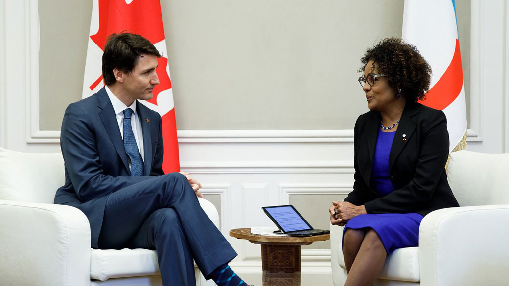 Le Premier ministre Justin Trudeau et Michaëlle Jean, secrétaire générale de l’Organisation internationale de la Francophonie, s'assoient et parlent devant les drapeaux du Canada et l'OIF