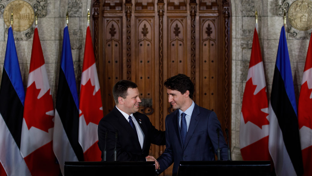 Prime Minister Justin Trudeau and the Prime Minister of Estonia, Jüri Ratas, shake hands at podiums in front of flags representing Canada and Estonia