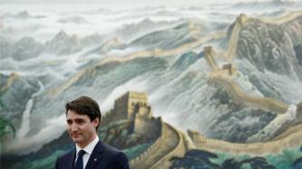 Prime Minister Justin Trudeau stands in front of a painting of the Great Wall of China