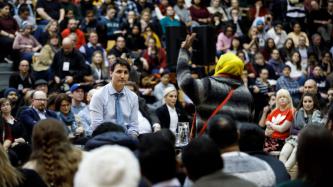 Prime Minister Justin Trudeau takes a question from an audience member during a town hall discussion in a gymnasium.