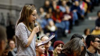 A young girl in the audience asks a question during a town hall discussion.