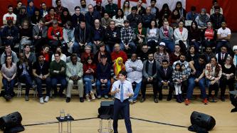 Prime Minister Justin Trudeau addresses the crowd during a town hall discussion in a gymnasium.