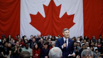 MP Terry Duguid addresses the crowd during a town hall discussion in a gymnasium.