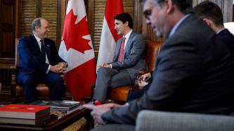 Prime Minister Justin Trudeau sits and talks with Prince Albert of Monaco while two other men sit in his office 