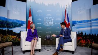 Prime Minister Justin Trudeau sits and talks with PM Theresa May.