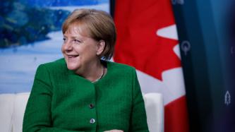 Chancellor Angela Merkel sits smiling during the discussion.