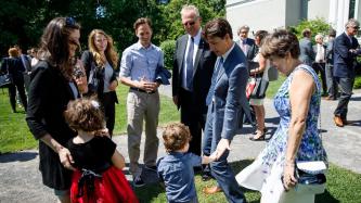 Le PM Trudeau tape dans la main d’un petit garçon, sous le regard de la famille