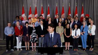 PM Trudeau speaks at the podium with Cabinet members behind him