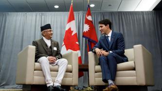 PM Trudeau sits and speaks to PM Oli