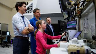 Ella-Grace uses a joystick and dial while PM Trudeau and others look on