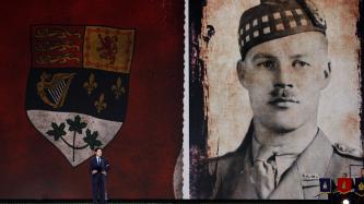 PM Trudeau on stage with a giant image of a fallen soldier