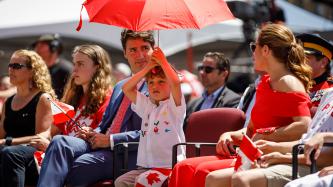 Hadrien Trudeau holds a red umbrella on his head