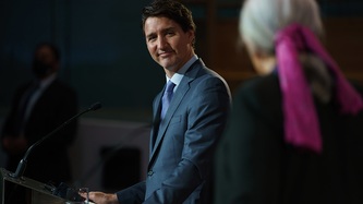 Prime Minister Justin Trudeau stands at podium smiling towards Ms. Mary Simon
