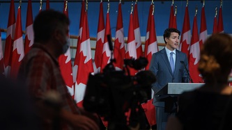 Prime Minister Justin Trudeau stands at a podium facing camera technicians