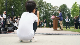 A young boy takes a photo of PM Trudeau at the podium