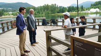 PM Trudeau and Premier Horgan speak with a man and his kids on a dock