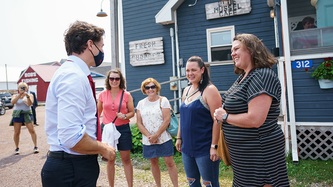 PM Trudeau and a group of people stand smiling at one another 