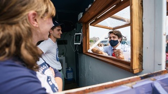 Two people look at PM Trudeau through a small window