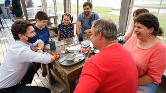 PM Trudeau is hunched down at a table where people are seated at an eatery