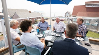 Le PM Trudeau est assis avec d’autres personnes à une table sur une terrasse