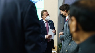 Le PM Justin Trudeau, en compagnie d’autres personnes, regarde un homme qui tient un papier