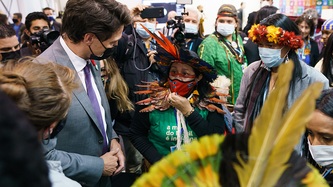 Le premier ministre Justin Trudeau regarde une jeune femme dans une foule de personnes et de caméras