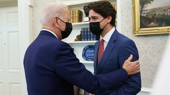 U.S. President Biden with his hand on Prime Minister Trudeau's shoulder look at one another