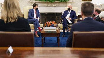 U.S. President Biden and Prime Minister Trudeau sit in front of a fireplace with others present