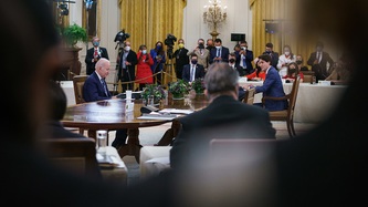 Media and others look on as U.S. President Biden and PM Trudeau sit at a large table